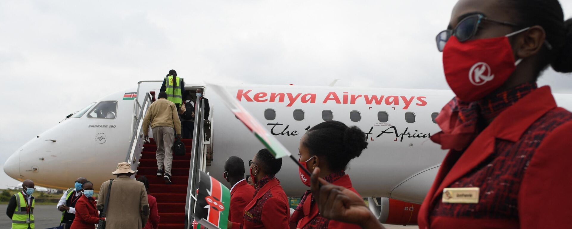 Kenya Airways cabin crew members (R), waive flags as they usher passengers at the Jomo Kenyatta International Airport (JKIA), after the official launch on resumption of local flights in Nairobi, on July 15, 2020.  - Sputnik International, 1920, 10.01.2023