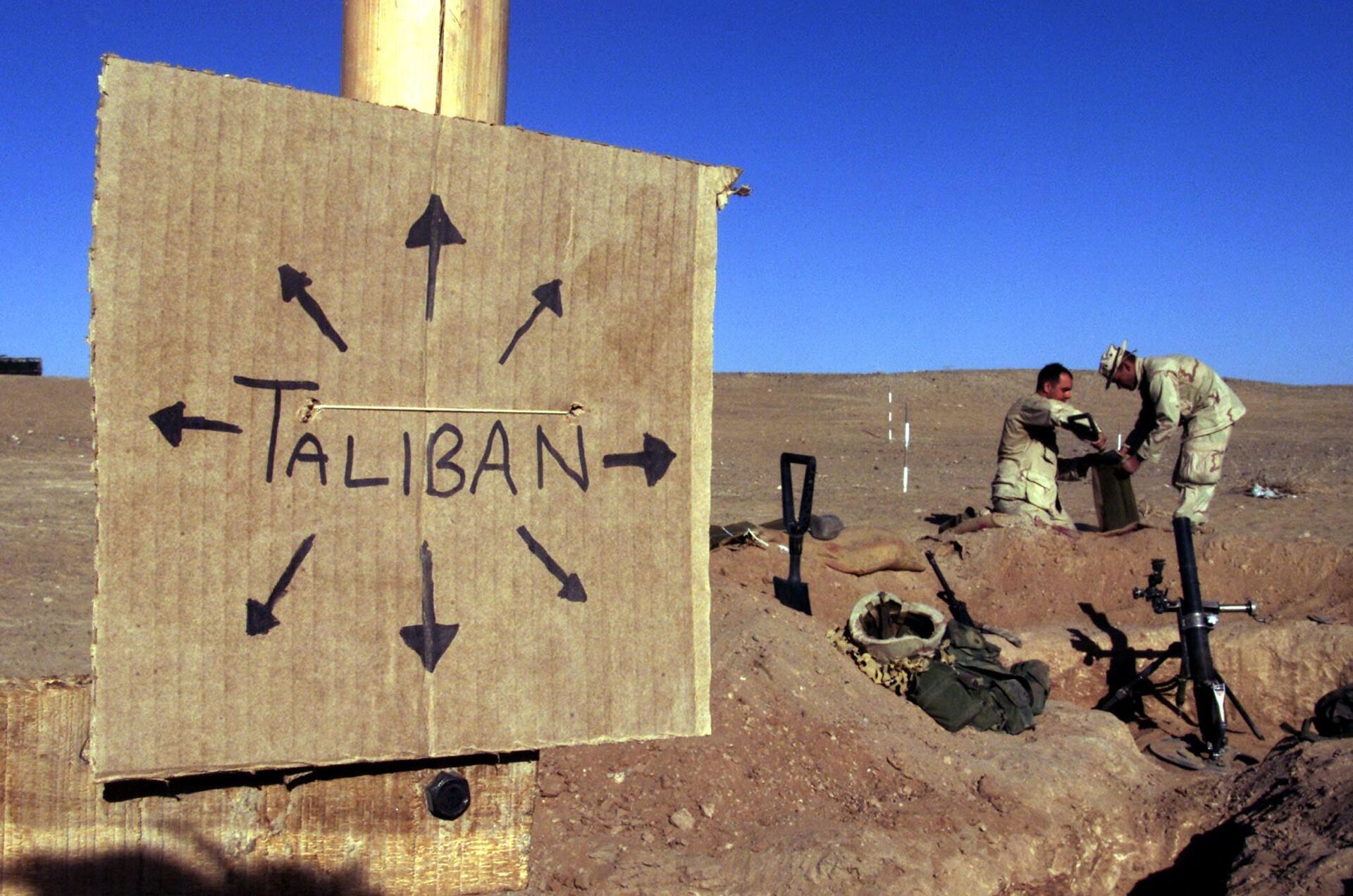 US Marines from Charlie 1/1 of the 15th Marine Expeditionary Unit fill sand bags around their light mortar position on the frontlines of the US Marine Corps base in southern Afghanistan 30 November 2001 near a cardboard sign reminding troops that Taliban forces could be anywhere and everywhere. - Sputnik International, 1920, 13.01.2023