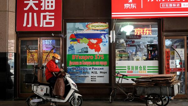A delivery man stands in front of an billboard advertising international logistics transportation to Russia, outside a convenience store in Ritan International Trade Center in Beijing on March 22, 2022. - Sputnik International