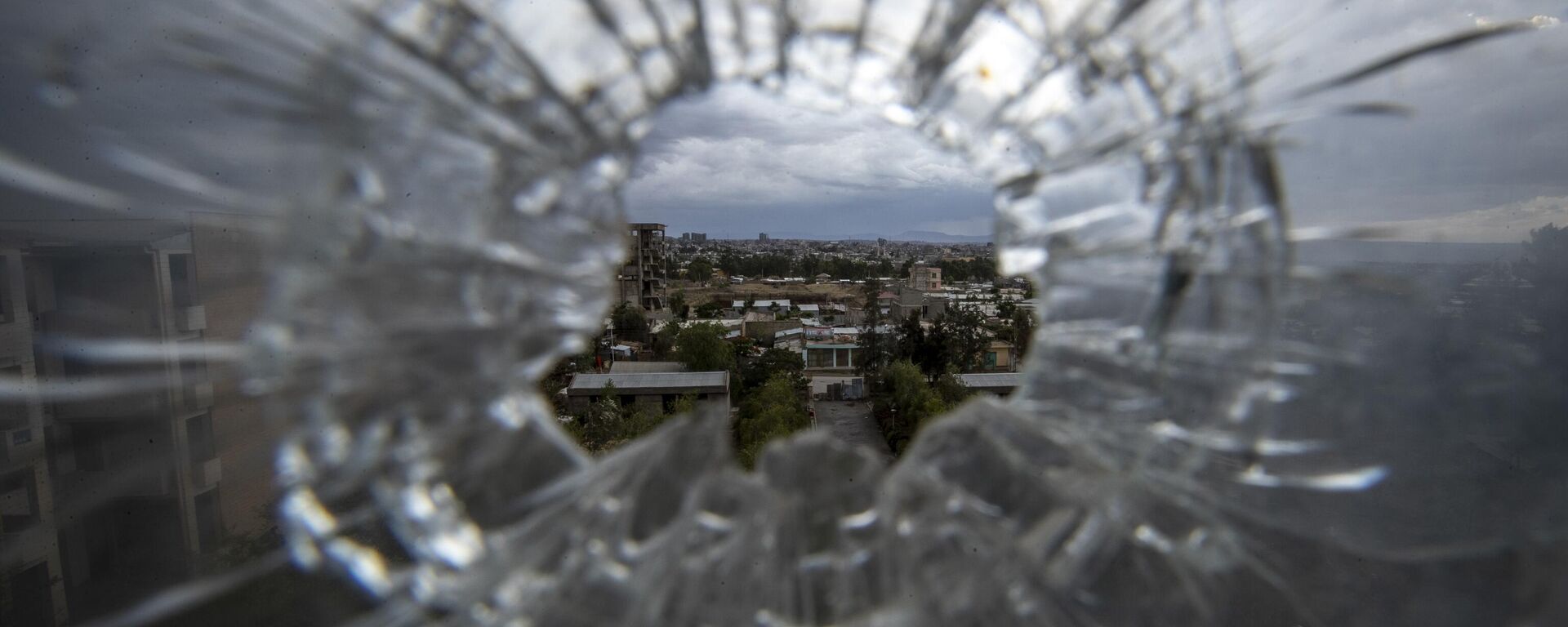 The city of Mekele is seen through a bullet hole in a stairway window of the Ayder Referral Hospital in the Tigray region of northern Ethiopia on May 6, 2021 - Sputnik International, 1920, 15.01.2023