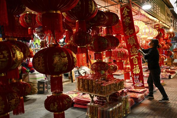 A vendor arranges Chinese lanterns and other decorations for sale for the upcoming Chinese Lunar New Year celebrations along a street in the county-level city of Ruili in Dehong prefecture, in China&#x27;s west Yunnan Province. - Sputnik International