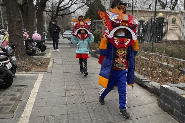 Children wearing cardboard lion dance masks walk along a street in Beijing. The lion dance is a traditional part of celebrations as well as the dragon dance, performed by professionals. - Sputnik International