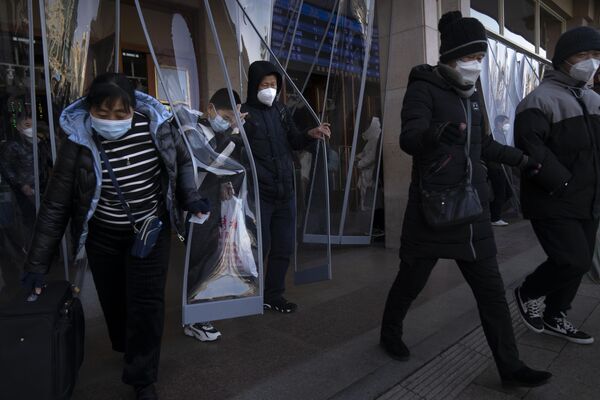 Travelers wearing face masks walk out of an exit of the Beijing Railway Station in Beijing. Millions of Chinese are expected to travel during the Lunar New Year holiday period this year. - Sputnik International