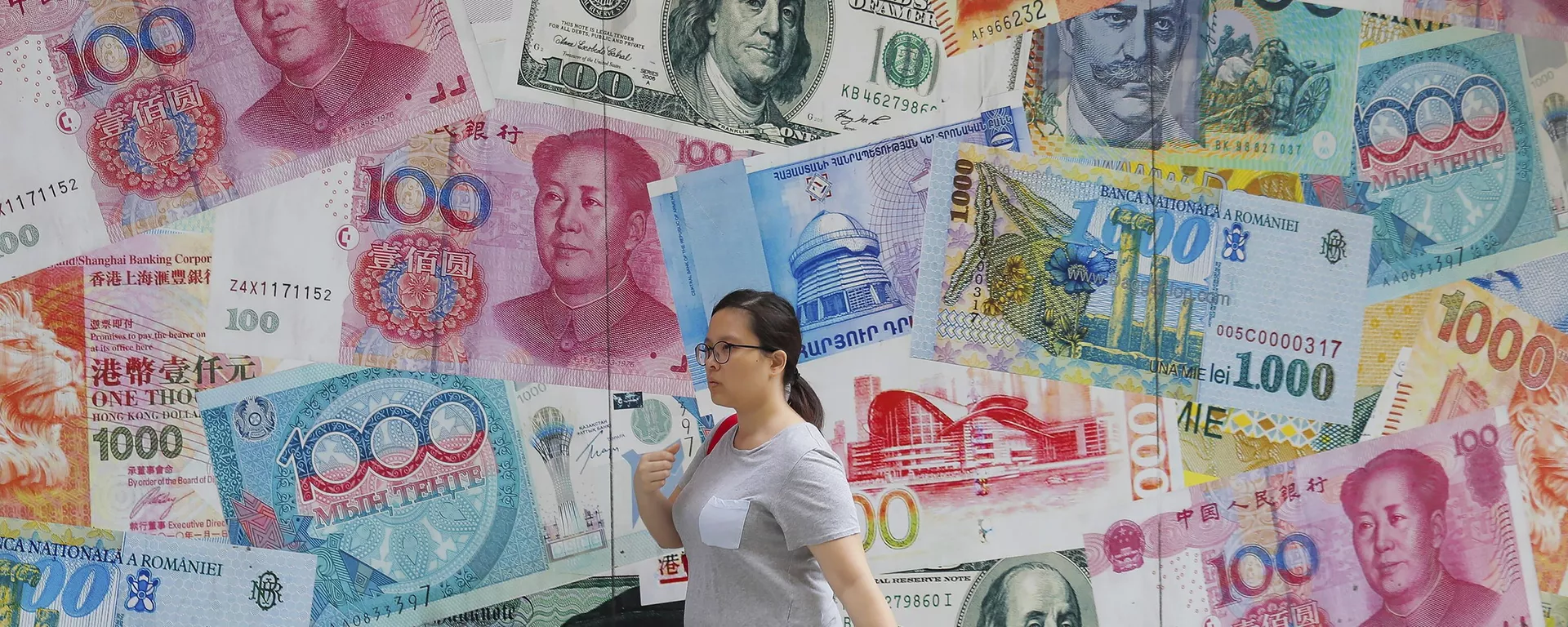 A woman walks by a money exchange shop decorated with banknotes of Chinese yuan and US dollars at Central, a business district in Hong Kong, Tuesday, Aug. 6, 2019. - Sputnik International, 1920, 11.07.2023