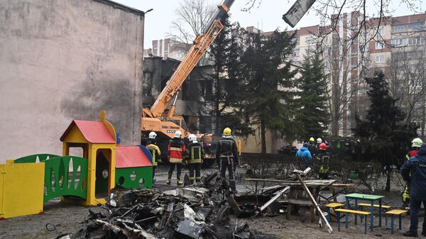 Firefighters work near the site where a helicopter crashed near a kindergarten in Brovary, outside the capital Kiev on January 18, 2023 - Sputnik International