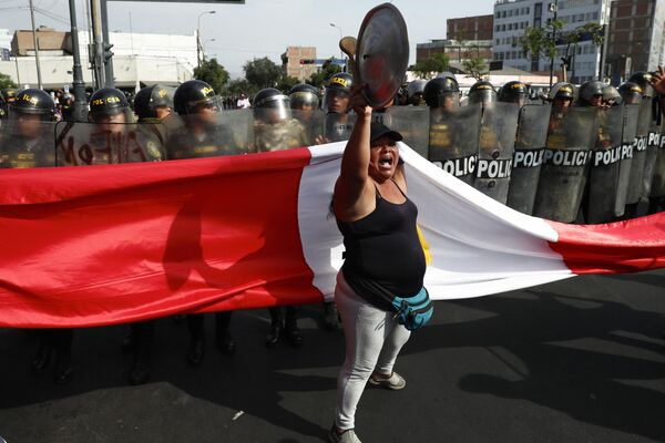 An anti-government protester stand in front of police blocking a march against President Dina Boluarte in Lima, Peru, Thursday, January 19, 2023.  - Sputnik International