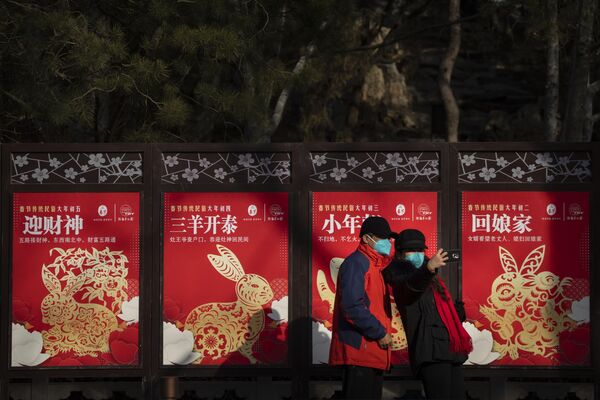 Visitors wearing masks pose in front of a row of Year of the Rabbit-themed billboards at a public park in Beijing on the first day of the Lunar New Year holiday on Sunday, 22 January 2023. - Sputnik International