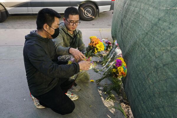 Two men place flowers near Star Dance Studio to honor victims killed in a shooting in Monterey Park, California on Sunday 22 January 2023. - Sputnik International