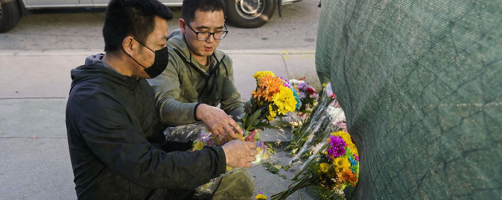 Two men place flowers near Star Dance Studio to honor victims killed in a shooting in Monterey Park, Calif., Sunday, January 22, 2023.  - Sputnik International, 1920, 24.01.2023