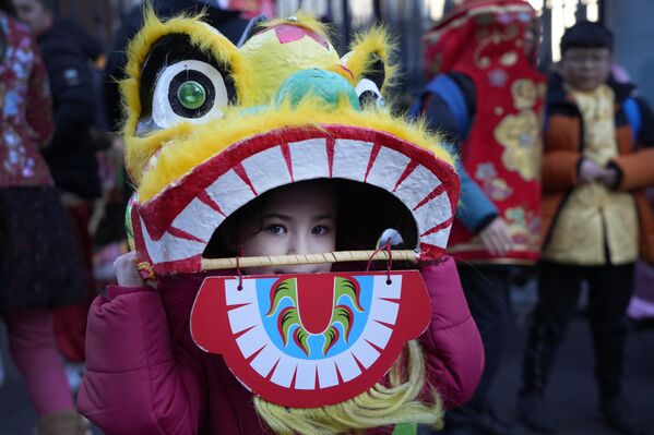 A performer looks out of a dragon mask before the Lunar New Year parade in London, on Sunday 22 January 2023. The parade celebrated the arrival of the Year of the Rabbit, with thousands of onlookers enjoying the spectacular show and Lion Dances in the capital. - Sputnik International