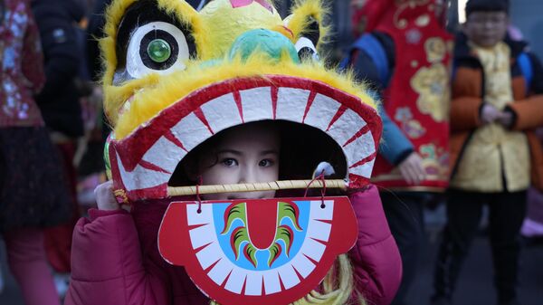 A young performer looks out of a dragon mask ahead of the Lunar New Year parade in London, Sunday, Jan. 22, 2023. The parade is to mark the arrival of the Year of the Rabbit, with thousands of visitors expected to watch the spectacular show and Lion Dances in the capital.  - Sputnik International