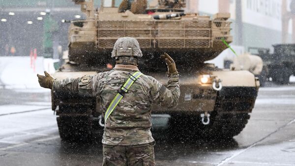 A US Army soldier signals the way to a M1A2 Abrams battle tank that will be used for military exercises by the 2nd Armored Brigade Combat Team, at the Baltic Container Terminal in Gdynia on December 3, 2022 - Sputnik International