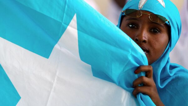 A Somali woman holds the national flag during a ceremony marking President Sheikh Sharif Sheikh Ahem's first year in office at the Villa Somalia presidential palace in Mogadishu on January 29, 2010 - Sputnik International