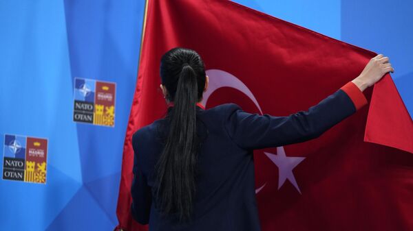 A member of the Turkish delegation adjusts the flag prior to an address by Turkish President Recep Tayyip Erdogan at a NATO summit in Madrid, Spain  - Sputnik International