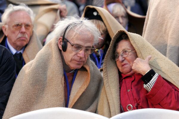 Jewish Holocaust survivors with their relatives cover themselves from the rain before the start of the ceremony at the Yad Vashem Holocaust memorial in Jerusalem in 2005, on Holocaust remembrance day, at the start of the annual commemorations for victims of the Nazi genocide. AFP PHOTO/MENAHEM KAHANA (Photo by MENAHEM KAHANA / AFP) - Sputnik International