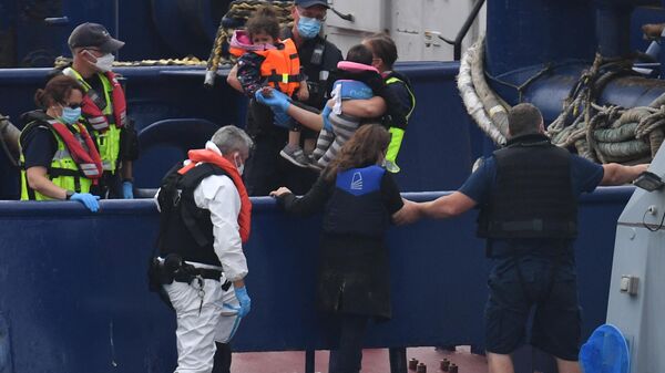 UK Border Force officials carry children intercepted whilst travelling in a RIB from France to England from their patrol vessel HMC Eagle after arriving at the Marina in Dover, southeast England on August 14, 2020 - Sputnik International
