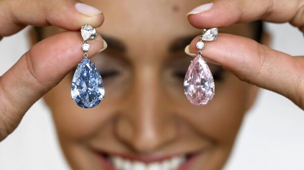 A model poses with the The Apollo Blue and The Artemis Pink diamonds, mounted as earrings, during a press preview by Sotheby's auction house, on May 11, 2017 in Geneva. - Sputnik International