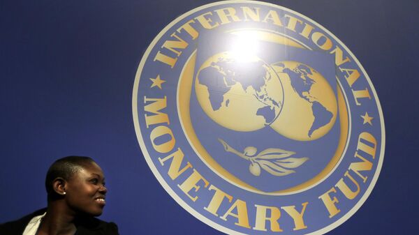 A woman sits in front of an International Monetary Fund logo at the venue of the IMF and World Bank meeting, Wednesday, Oct. 10, 2012. - Sputnik International