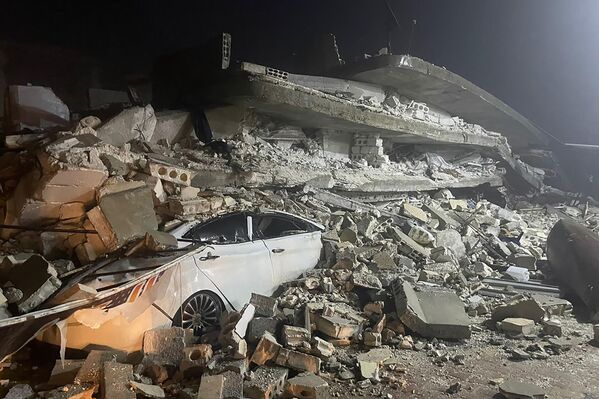 A car is seen under the wreckage of a collapsed building, in Azmarin town, in Idlib province, northern Syria, Monday, Feb. 6, 2023. (AP Photo/Ghaith Alsayed) - Sputnik International