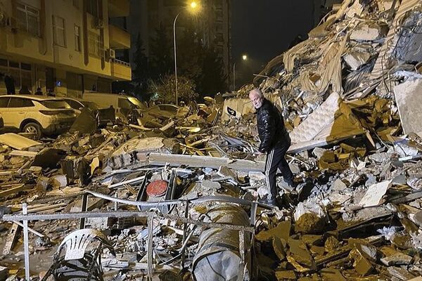 A man searches collapsed buildings in Diyarbakir, southern Turkey, early Monday, Feb. 6, 2023. (Depo Photos via AP) - Sputnik International