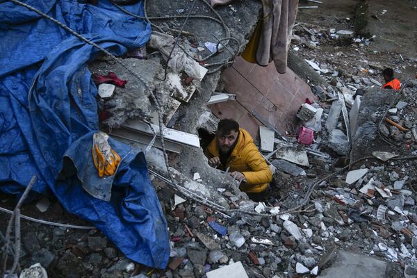 A man searches for people in a destroyed building in Adana, Turkey on Monday 6 February 2023. A powerful quake knocked down several buildings in south-east Turkey and Syria causing thousands of casualties. - Sputnik International