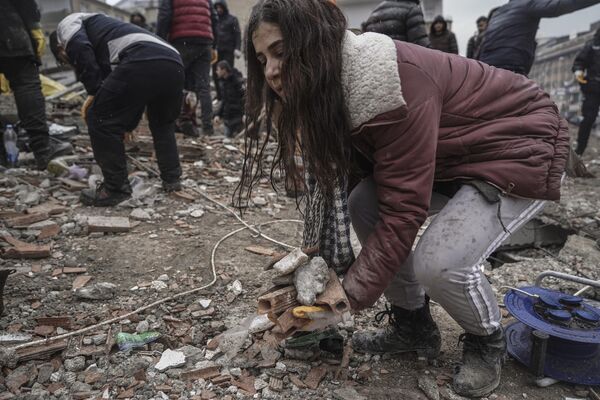 A young woman removes debris from a destroyed building as she searches for people with emergency teams in Gaziantep, Turkey on Monday 6 February 2023. - Sputnik International