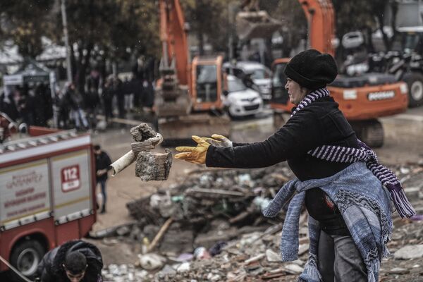 A woman removes debris from a destroyed building as she searches for people with emergency teams in Gaziantep, Turkey on Monday 6 February 2023. - Sputnik International