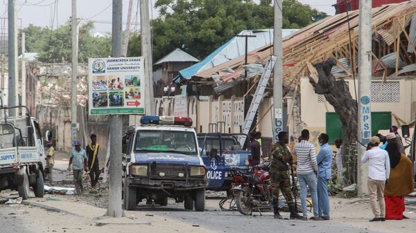 Police officers and people stand at the bomb explosion site in Mogadishu, Somalia, on November 25, 2021. - Sputnik International