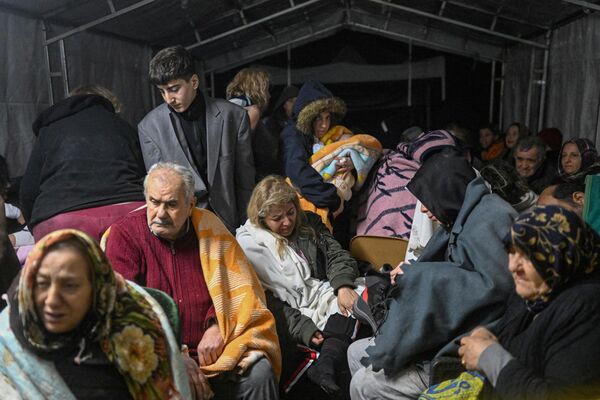Earthquake survivors sit sheltering in a tent in Hatay, the day after a 7.8-magnitude earthquake struck the country&#x27;s south-east. - Sputnik International