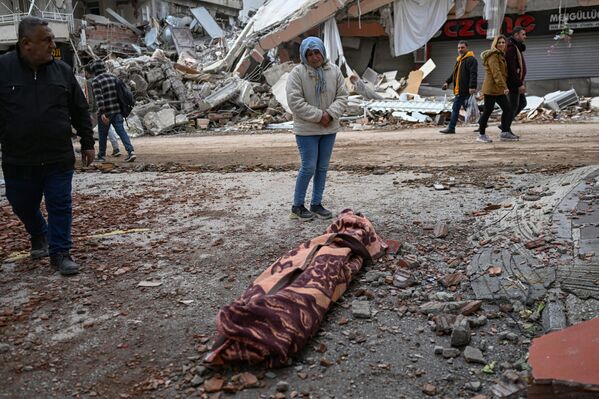 A woman weeps as she stands beside the body of a victim in Hatay on 7 February 2023, a day after a 7.8-magnitude earthquake struck the country&#x27;s south-east. - Sputnik International