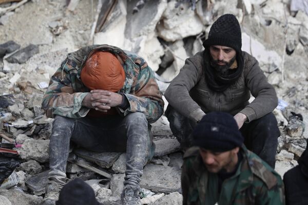 People sit in the wreckage of collapsed buildings, in Aleppo, Syria on Tuesday 7 February 2023. - Sputnik International