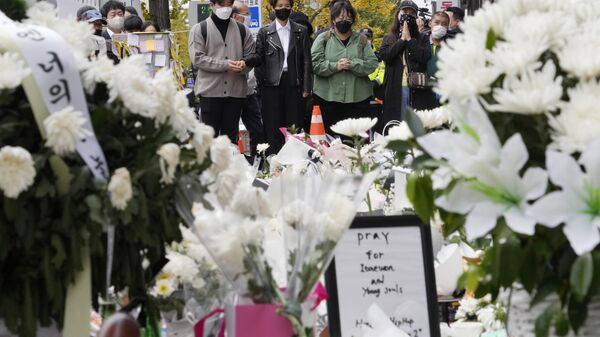 People pay tribute to victims of a deadly crowd surge that killed over 150 people in the neighborhood of Itaewon during Saturday night's Halloween festivities, at a makeshift flower-laying area set up near the scene of the accident in Seoul, South Korea, Thursday, Nov. 3, 2022 - Sputnik International