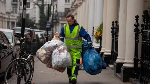 Local councils provide hundreds of services, such as rubbish and waste collection and disposal. A waste collector picks up garbage bags from the Royal Borough of Kensington and Chelsea in London on March 20, 2015.  - Sputnik International