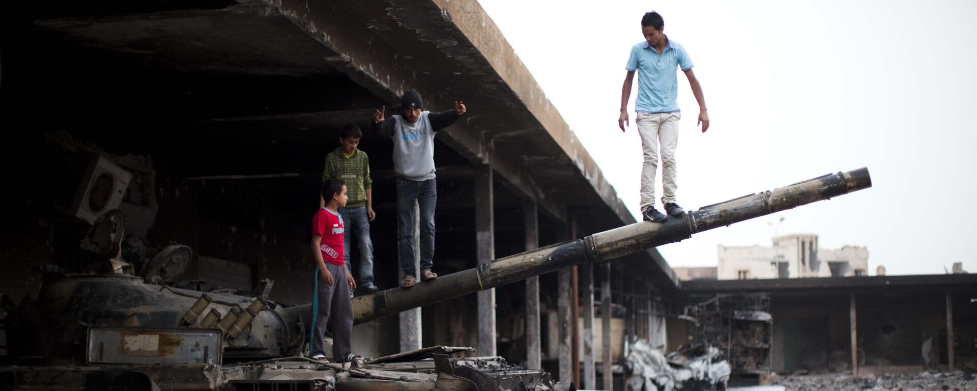 Boys play on a destroyed tank inside a vegetable market in Tripoli Street, the former center of fighting between the rebels and Moammar Gadhafi's forces in Misrata, Libya, Sunday, May 22, 2011.   - Sputnik International, 1920, 15.02.2023