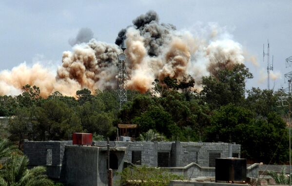 Smoke billows out from behind the trees after an air raid on the area of Tajura, 30km east of Tripoli, as loud explosions rocked the Libyan capital on 24 May 2011 when NATO unleashed a blitz oh the area in a bid to speed up the removal of Libyan leader Muammar Gaddafi.  - Sputnik International