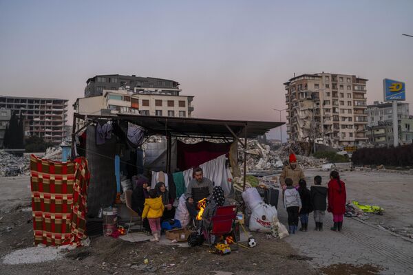 A family stays in a makeshift tent surrounded by buildings that were heavily affected during the earthquake in Antakya, south-eastern Turkiye on Tuesday 14 February 2023. - Sputnik International