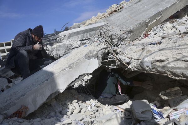 People try to remove their furniture and household appliances from a collapsed building after a devastating earthquake in the town of Jinderis, Aleppo province, Syria on Tuesday 14 February 2023. - Sputnik International