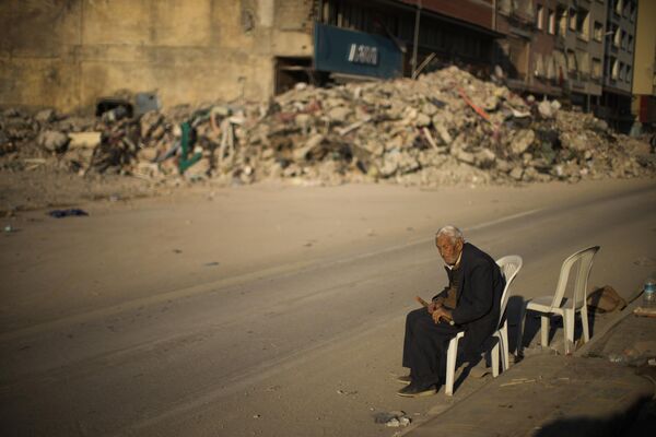 A man sits on a chair next to rubble of a destroyed building in Iskenderun city, southern Turkiye on Tuesday 14 February 2023. - Sputnik International