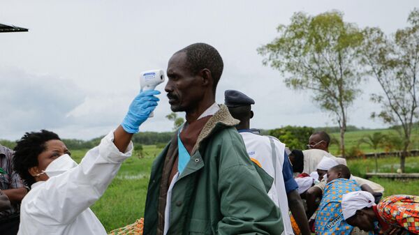 A medical staff member measures a man's temperature as a preventive measure against the COVID-19 coronavirus on his arrival of repatriation in Gatumba, on border with the Democratic Republic of Congo (DRC), in Burundi, on March 18, 2020 - Sputnik International