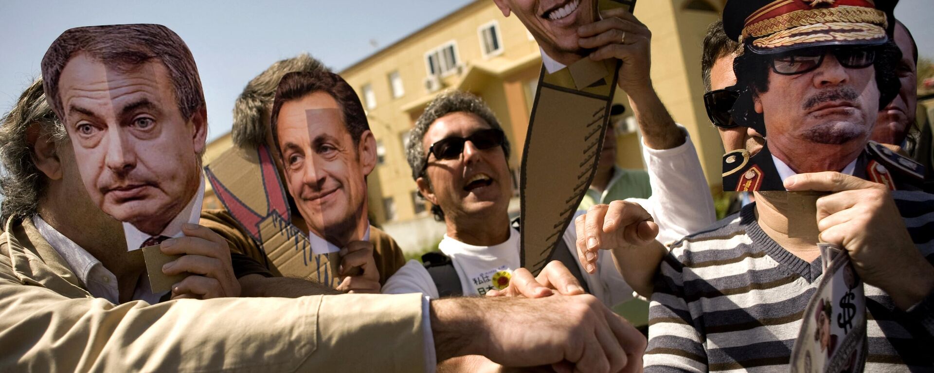 Protesters wearing masks featuring (L-R) Spanish Prime Minister Jose Luis Rodriguez Zapatero, French President Nicolas Sarkozy, US President Barack Obama, Libyan leader Moamer Kadhafi take part in an anti-war demonstration calling on  governments to stop bombing Libya in front of the Base Naval de Rota, on March 26, 2011, in Rota near Cadiz. - Sputnik International, 1920, 15.02.2023