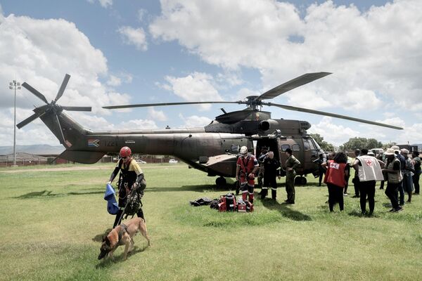 South African Defence Force (SADF) officers and members of South African Police Service (SAPS) belonging to the K9 Unit created for search and rescue in land/water environment stand in front of an SADF helicopter directed to Mekemeke village by Mhlambanyatsi river, province of Mpumalanga, on February 16, 2023. - Sputnik International