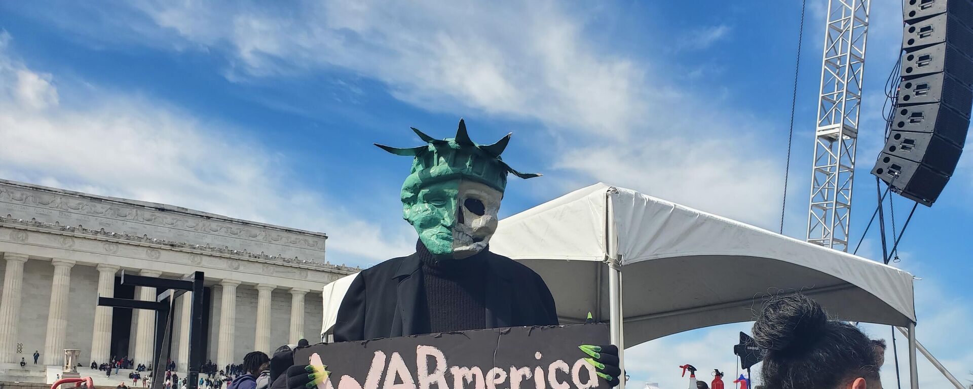 A protester holds a sign saying WARmerica at the Rage Against the War Machine Rally in Washington DC on February 19, 2023 - Sputnik International, 1920, 20.02.2023