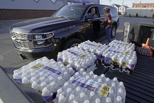 Becky Rance, center, talks with a police officer as she hands out water from the back of her truck in downtown East Palestine, Ohio, as the cleanup of portions of a Norfolk Southern freight train continues. (AP Photo/Gene J. Puskar) - Sputnik International