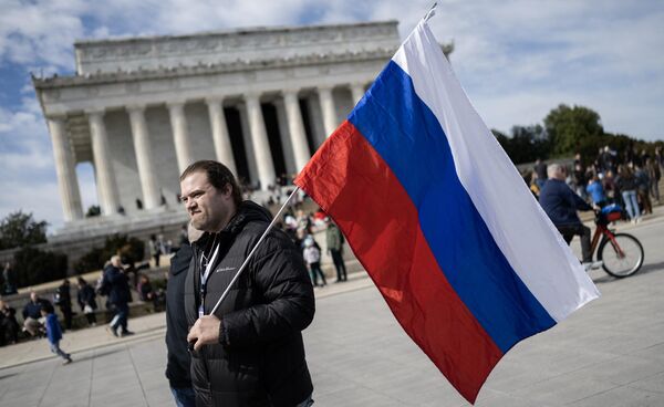 Ryan Cotton carries a Russian National flag during an antiwar rally at the Lincoln Memorial in Washington, DC, on February 19, 2023. - Sputnik International