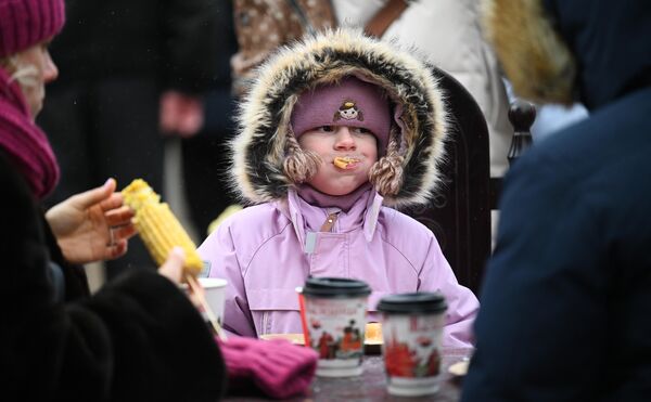 A girl eats pancakes at the Maslenitsa festival in Central Moscow. - Sputnik International