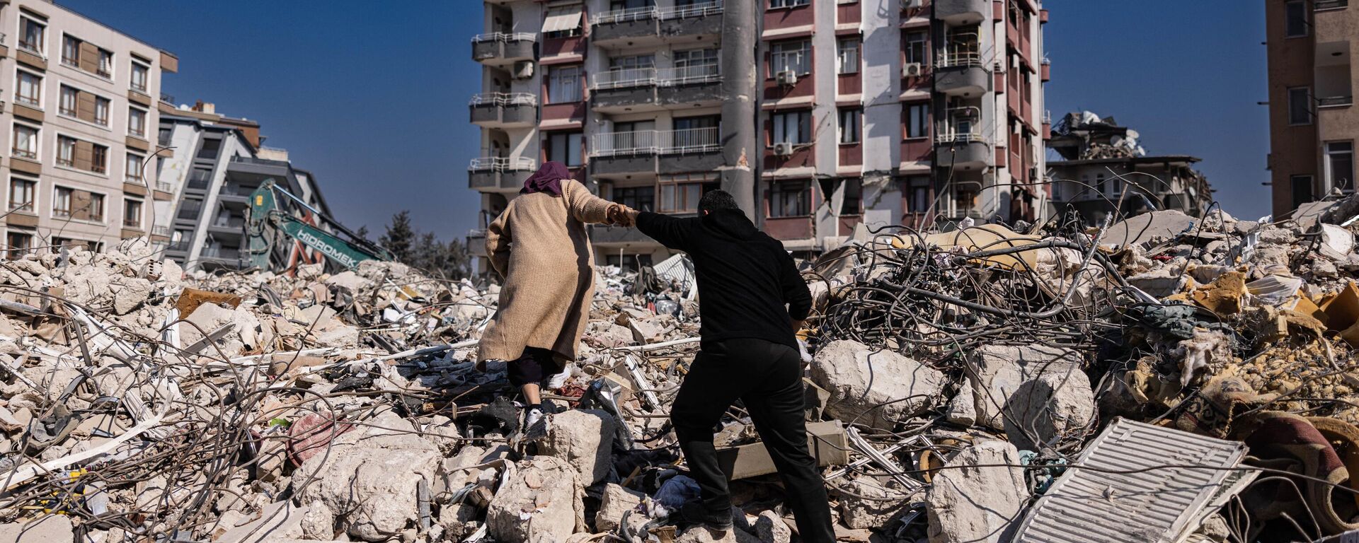 A couple climbs the rubble of collapsed buildings in Antakya, southern Turkey on February 20, 2023. - Sputnik International, 1920, 21.02.2023