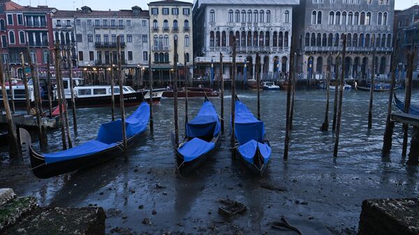 This photograph taken on February 20, 2023, shows gondolas tied up in Venice Canal Grande, during a severe low tide in the lagoon city of Venice. - Sputnik International