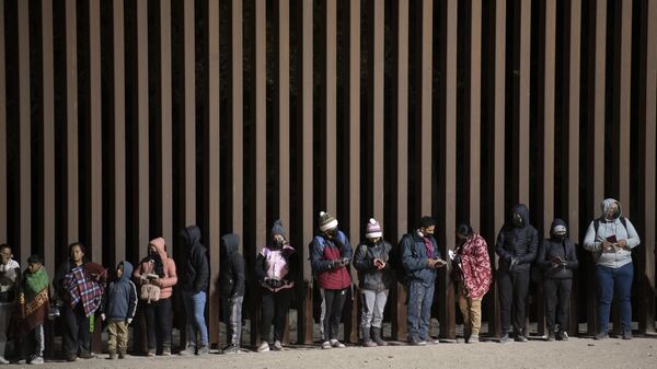 Asylum-seekers line up to be processed by US Customs and Border Patrol agents at a gap in the US-Mexico border fence near Somerton, Arizona, on December 26, 2022. - Sputnik International