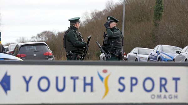 Armed police officers stand guard at the scene of a shooting of an off duty policeman  at the Killyclogher Road sports complex in the northern Irish town of Omagh - Sputnik International