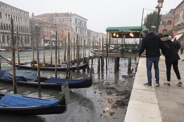People look at gondolas docked along a canal during a low tide in Venice, Italy. - Sputnik International